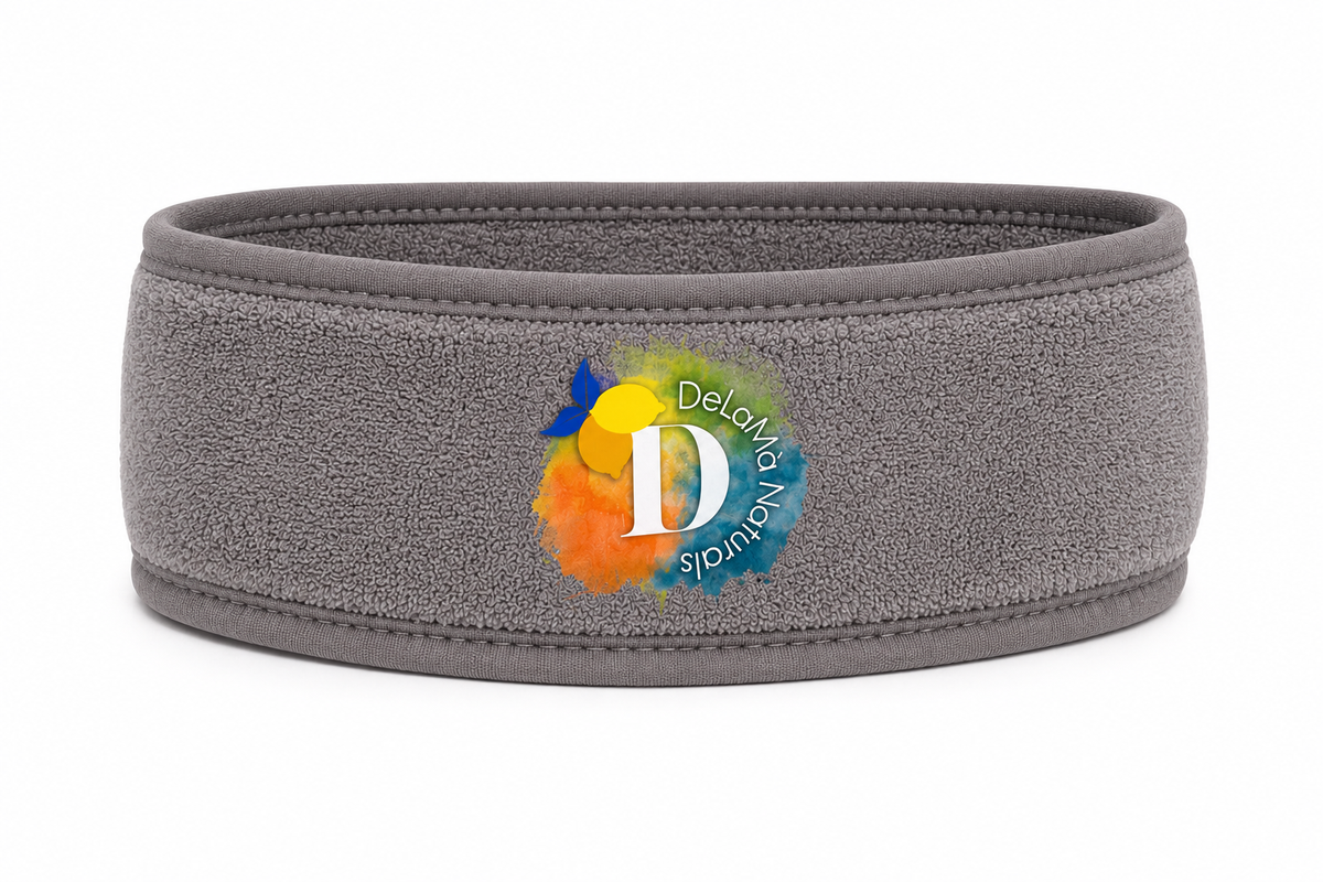 A gray textured athletic headband with a colorful circular logo in the center featuring a large white letter 'D' and the words 'DeLaMà Naturals'.